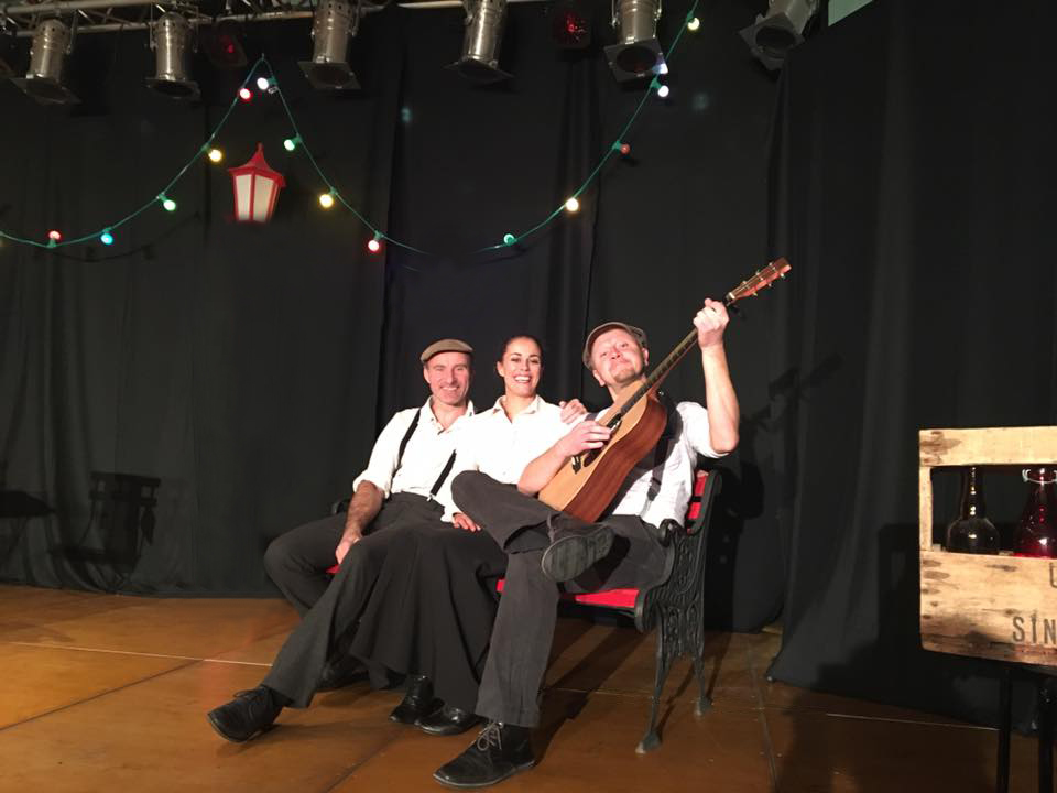 Comédiens des Amants de Montmartre interprétant une scène musicale avec guitare sur scène.